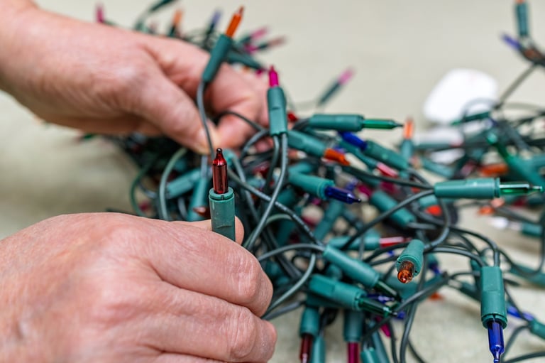 Person checking colored Christmas tree lights before decorating